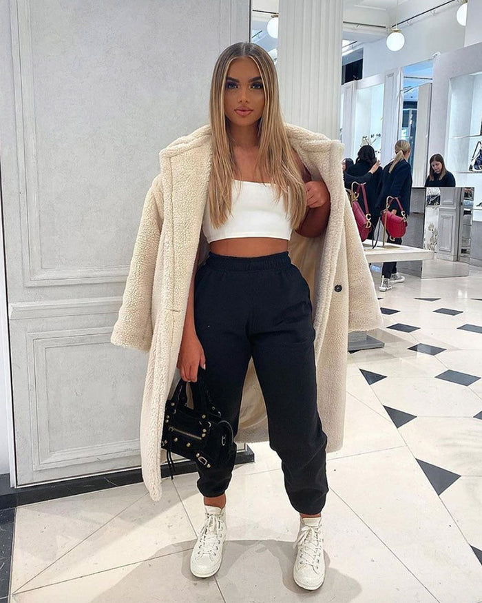 chic young lady standing in a mall wearing loungewear and a prague white oversized faux fur teddy coat
