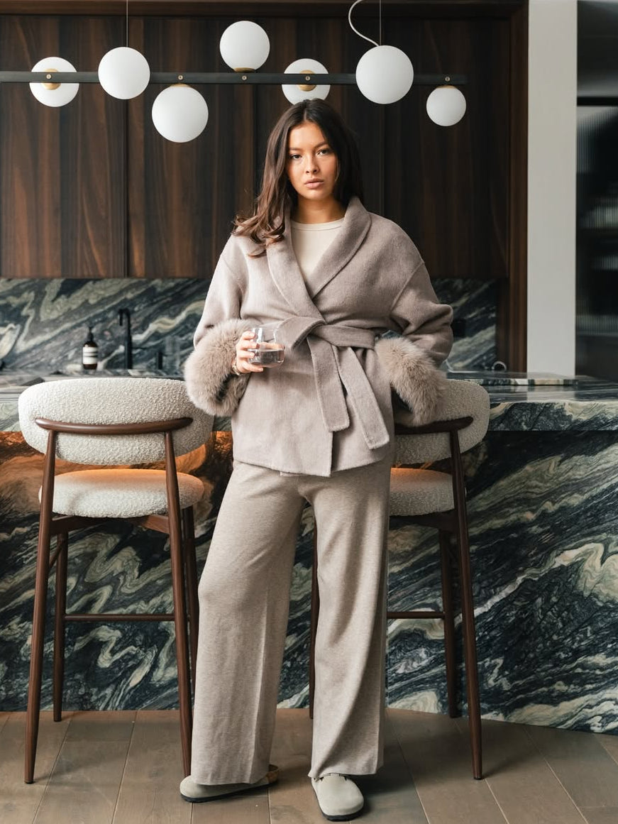 Woman in a stylish outfit standing in a modern interior setting with marble walls.